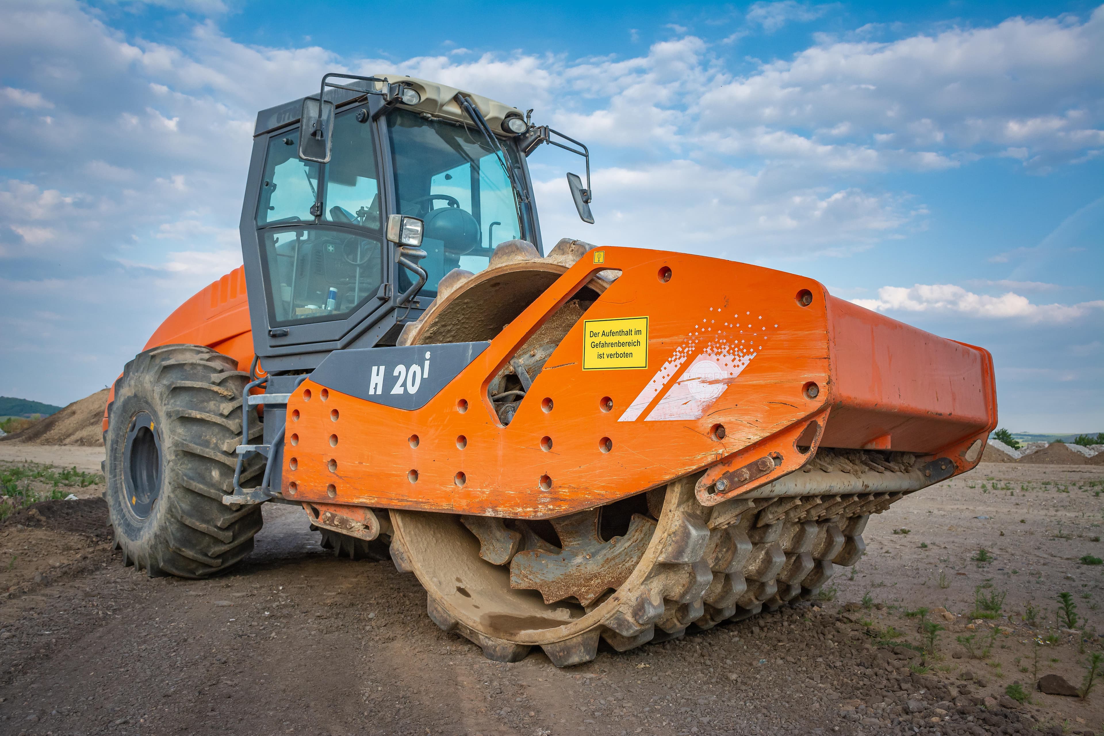 Orange road roller on a construction site